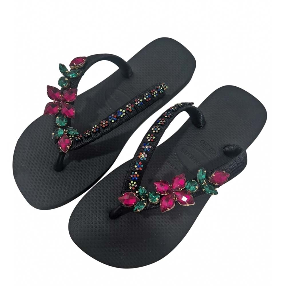 Chanclas tipo Havaianas en color negro, decoradas con pedrería brillante y flores fucsia.