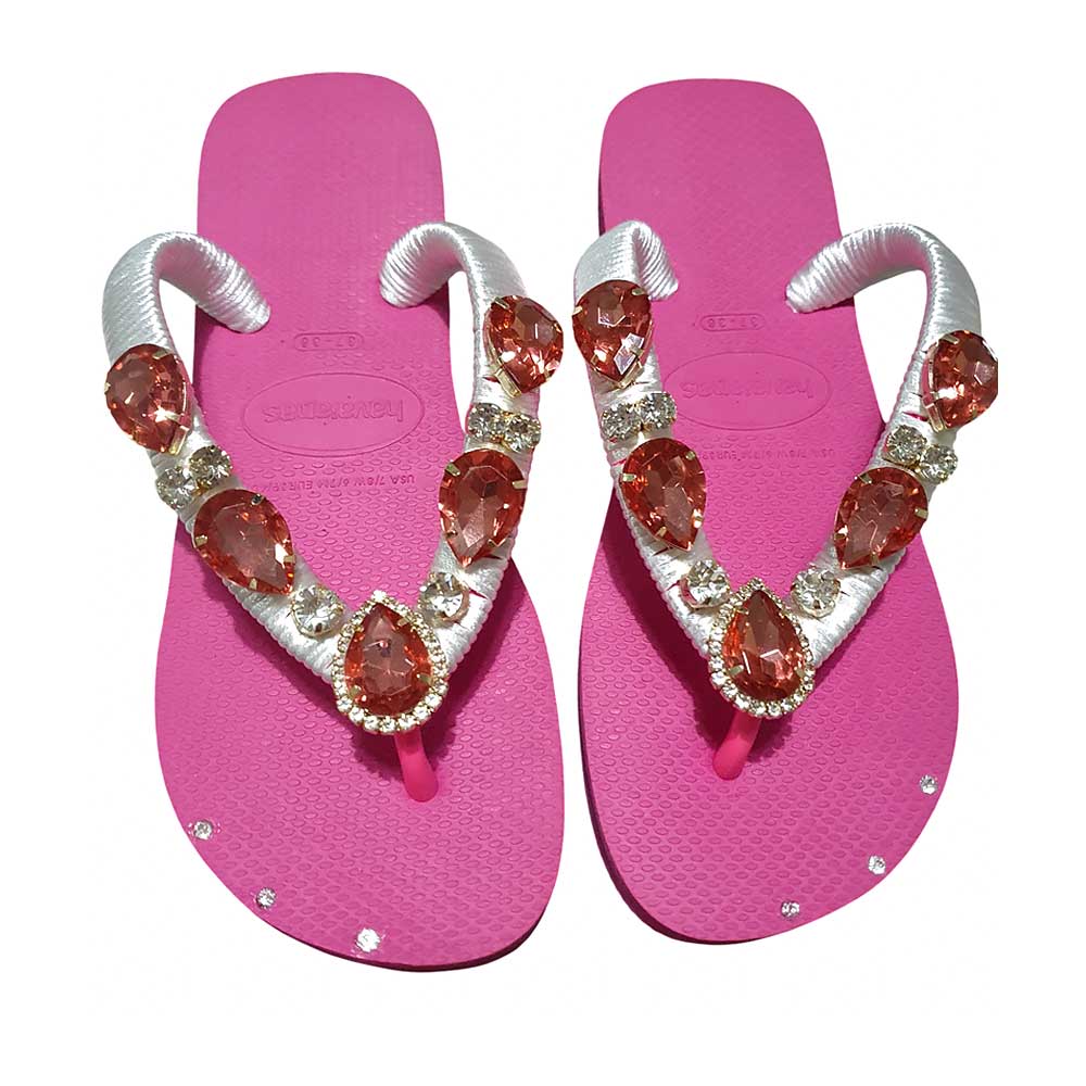 Chanclas Havaianas de color fucsia con tiras blancas decoradas con pedrería roja.