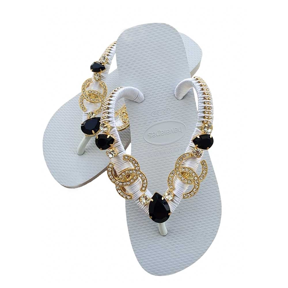 Chanclas Havaianas color blanco con detalles en dorado y pedrería negra.