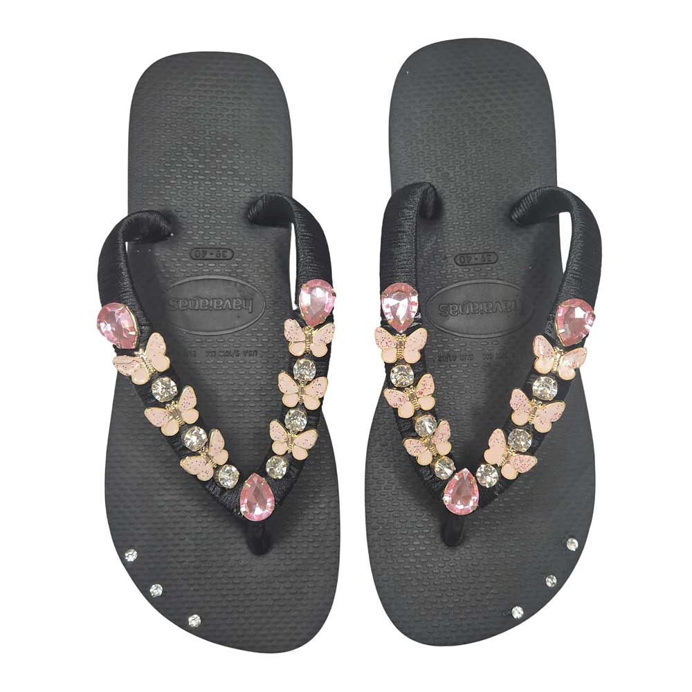 Chanclas tipo havaianas de color negro decorada con mariposas y piedras en rosa.